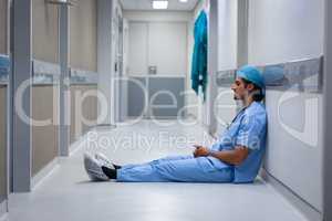 Male surgeon leaning at hospital corridor