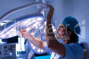Male surgeon fixing surgical light at hospital