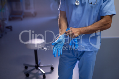 Male surgeon wearing rubber gloves in hand