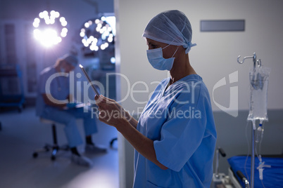 Female surgeon using digital tablet in operation room