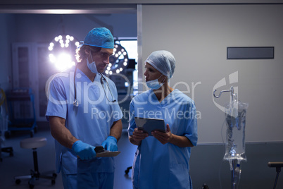 Surgeons interacting with each other while holding digital tablet at hospital