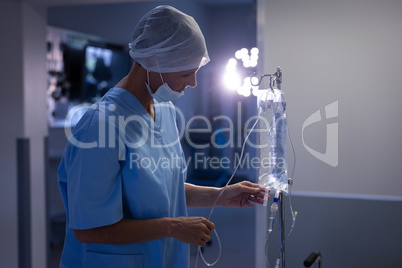 Female surgeon checking intravenous therapy drip at hospital