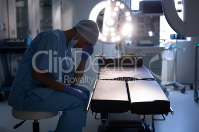 Nervous female surgeon sitting in operation room at hospital