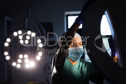Female surgeon fixing surgical light in operation room at hospital