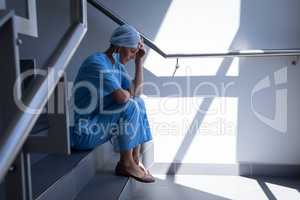 Upset female surgeon sitting on stair case in hospital