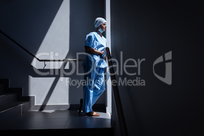 Female surgeon looking through the window in the hospital stairs