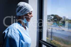 Female surgeon looking through the window while standing in the hospital