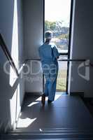 Female surgeon looking through the window in the hospital stairs