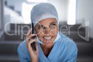 Female surgeon talking on mobile phone while sitting on hospital stair case