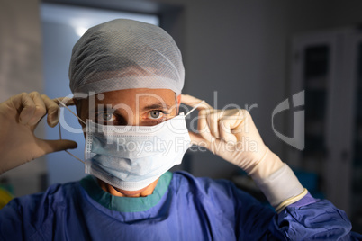 Female surgeon putting on medical mask before operation