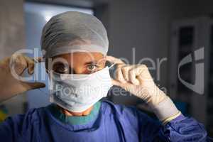 Female surgeon putting on medical mask before operation