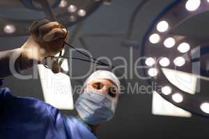 Mature female surgeon holding scissor in hand