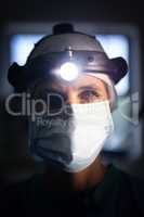 Mature female surgeon standing with surgical head lamp in hospital