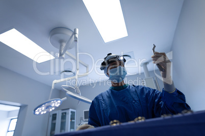 Female surgeon with surgical instrument in operation theater