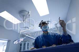 Female surgeon with surgical instrument in operation theater