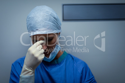 Upset female surgeon standing while leaning against the operating room door