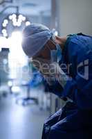 Upset female surgeon sitting  in operation room