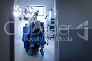 Upset female surgeon sitting on bed in operation room