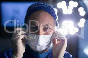 Female surgeon  putting on medical mask before operation