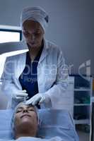 Surgeon giving plastic surgery injection on patient face