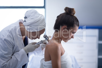 Female doctor checking patient with dermatoscopy