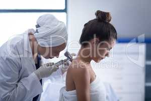 Female doctor checking patient with dermatoscopy