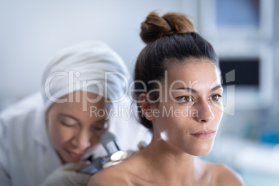 Female doctor checking patient with dermatoscopy