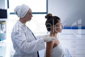 Mature female doctor giving massage to the woman in clinic
