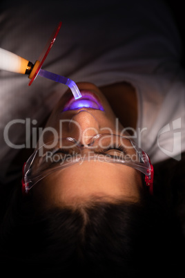 Dentist examining patient with dental curing light in clinic