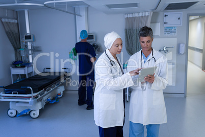 Matured female doctors discussing over digital tablet in clinic