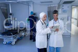 Matured female doctors discussing over digital tablet in clinic