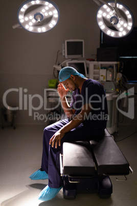 Nervous male surgeon sitting in operation room at hospital