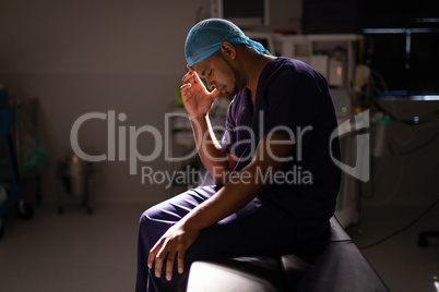 Nervous male surgeon sitting in operation room at hospital