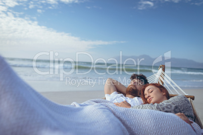 Couple sleeping on hammock at beach