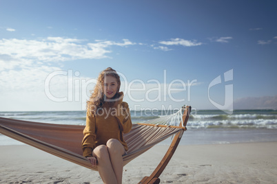 Woman looking at camera sitting on hammock at beach