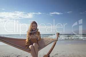 Woman looking at camera sitting on hammock at beach