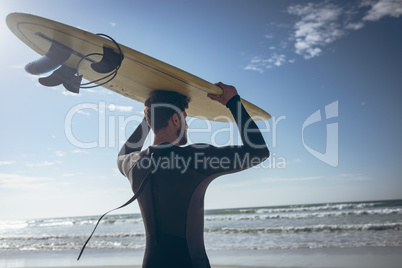 Male surfer holding surfboard at beach