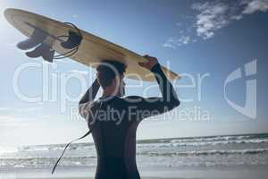 Male surfer holding surfboard at beach