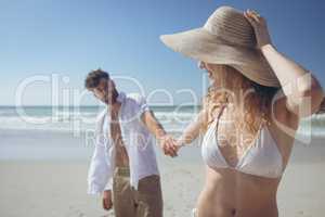 Couple holding hand while standing at beach