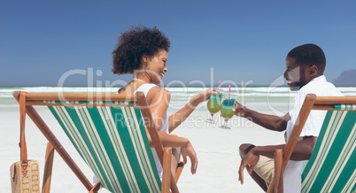 Young couple relaxing on sun lounger at beach on sunny day