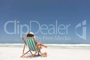 Young woman using digital tablet while sitting at sun lounger at beach