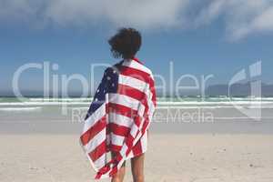 Woman wrapped american flag at beach