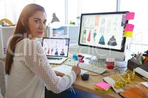Female fashion designer looking at camera while working at desk