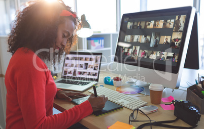 Female graphic designer working on graphic tablet at desk