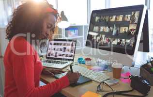 Female graphic designer working on graphic tablet at desk