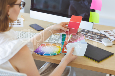 Graphic designer checks the color with color swatch at desk