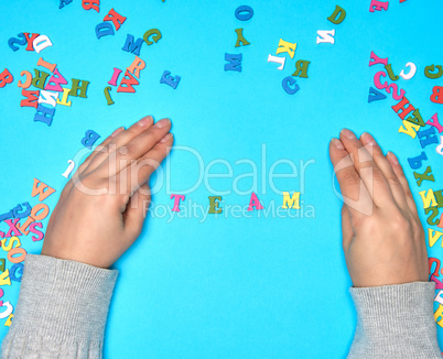 female hand and multicolored wooden letters of the English alpha