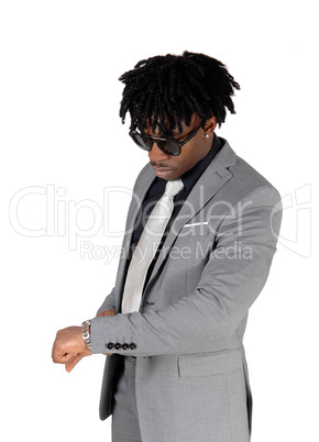 Black man standing looking at his watch
