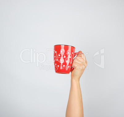 red ceramic cup in a female hand on a white background