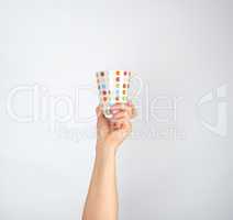 ceramic cup with multi-colored circles in a female hand on a whi